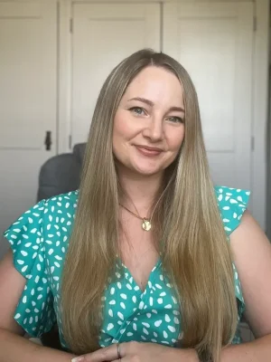 Victoria Steele, Founder & CEO of Bearhat Marketing – a marketing agency in the west midlands A 35 year old white woman with long brown hair, with arms resting on a desk. Wearing a green dress with white spots. Victoria Steele, Marketing Consultant in the Midlands.